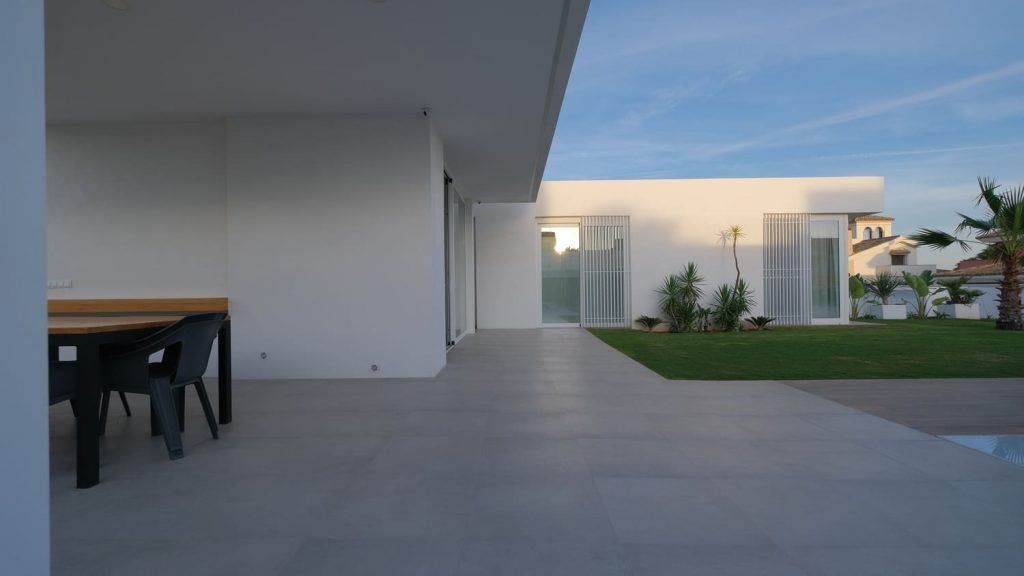 Porche de una vivienda unifamiliar terminada con suelo de gres y carpintería blanca